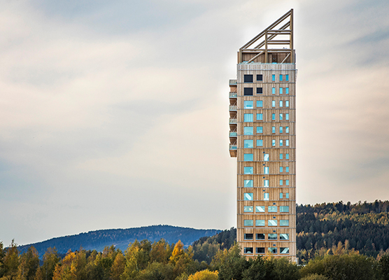 Edificio de madera más alto del mundo, con 18 pisos de altura. En el fondo a altura baja hay arboles y una montaña 